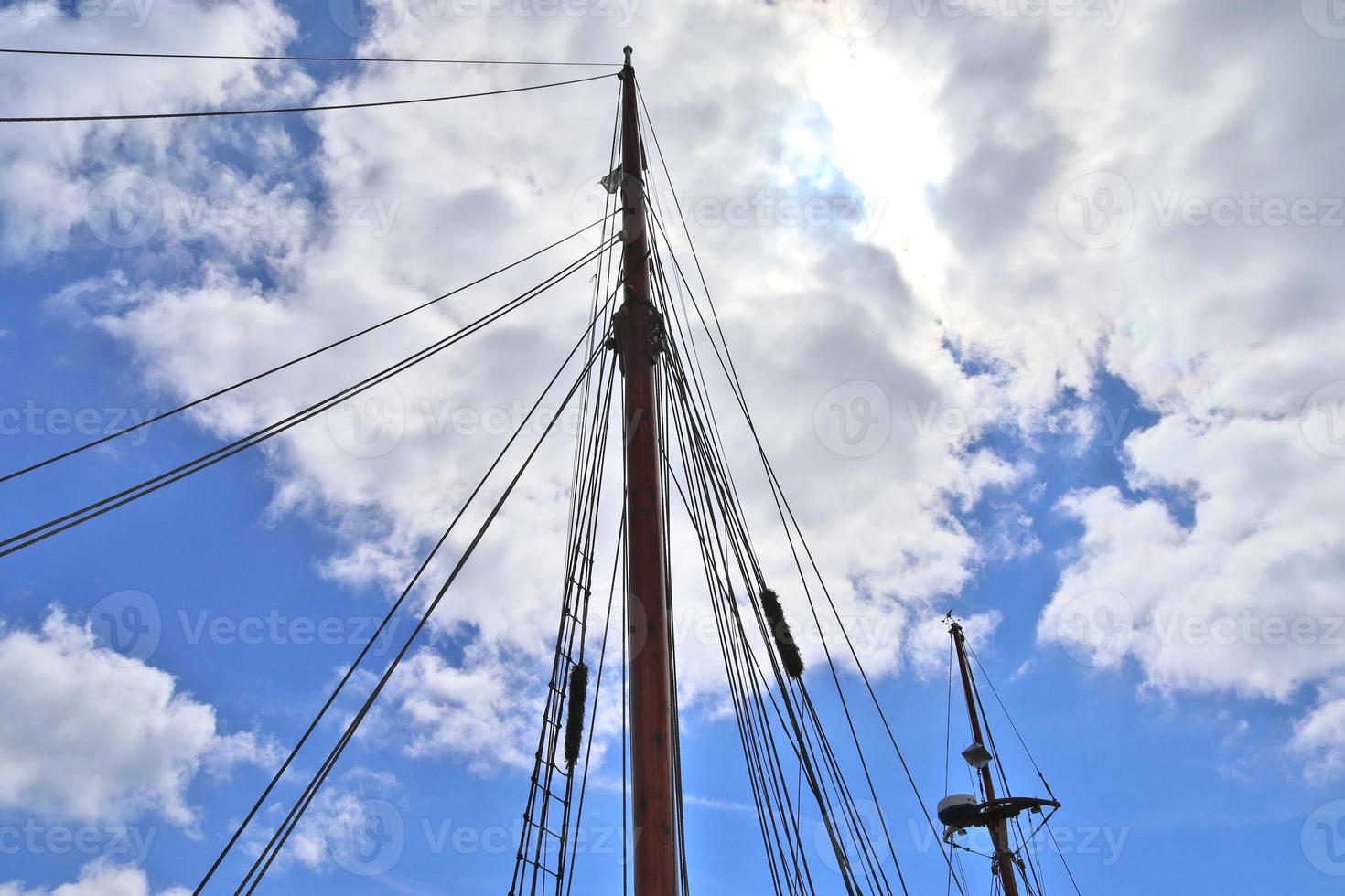 Sailing ship mast against the blue sky on some sailing boats with rigging details. photo