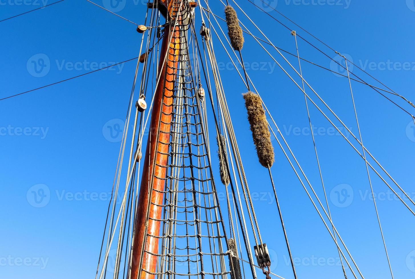 Sailing ship mast against the blue sky on some sailing boats with rigging details. photo