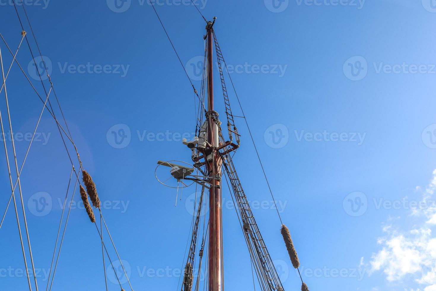 Sailing ship mast against the blue sky on some sailing boats with rigging details. photo