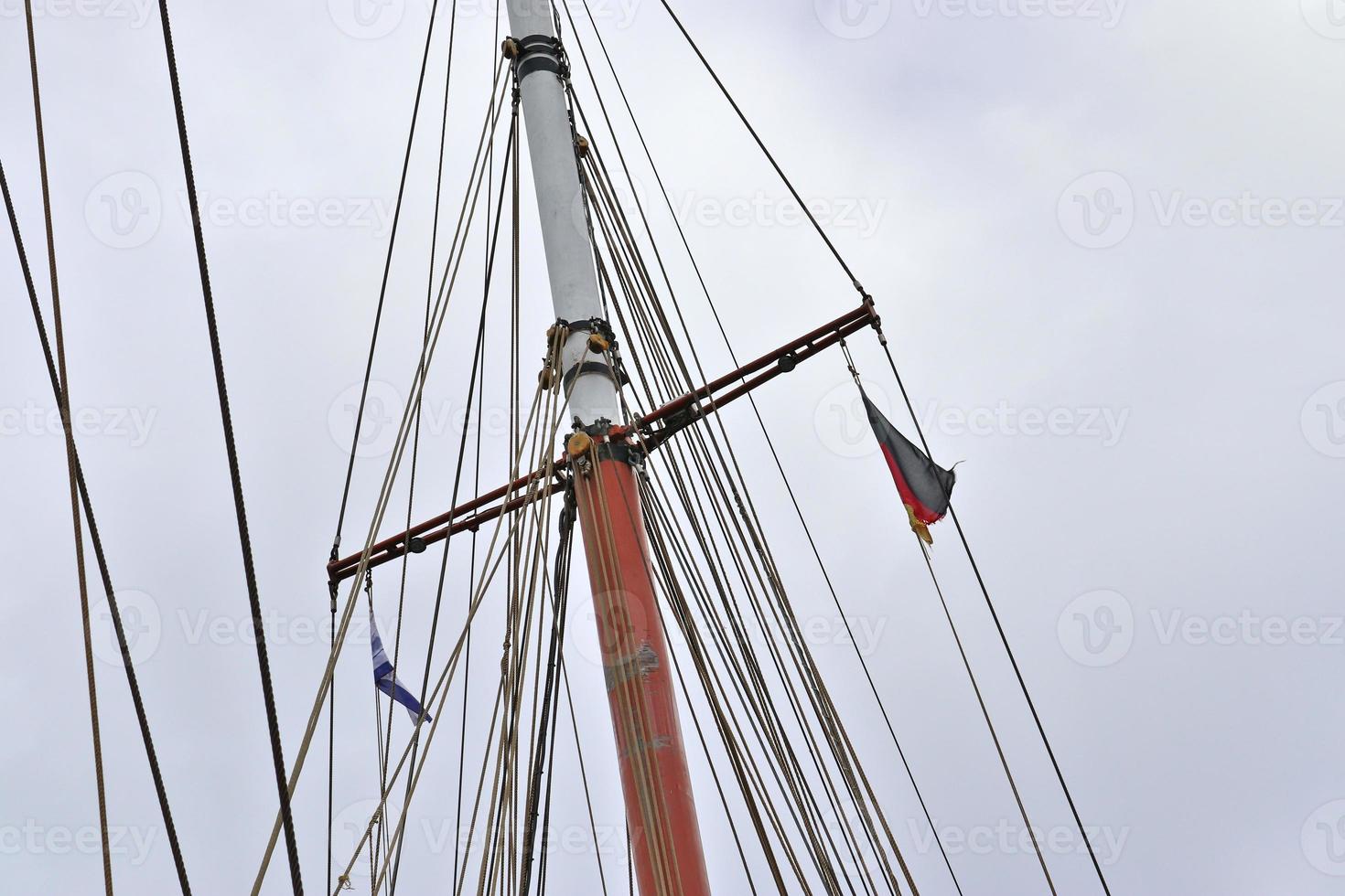 Sailing ship mast against the blue sky on some sailing boats with rigging details. photo