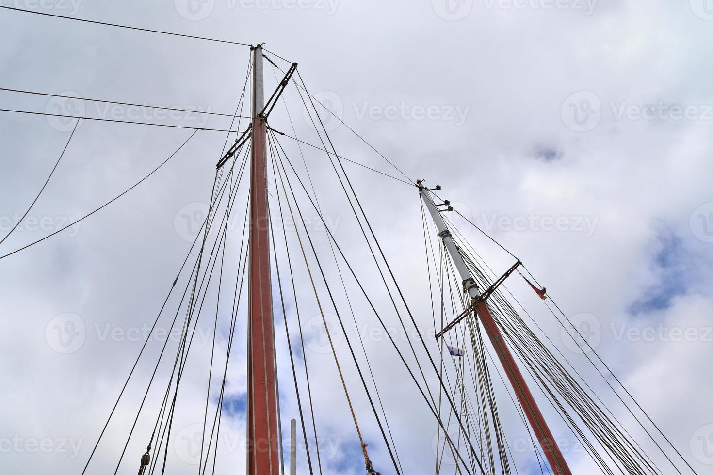 Sailing ship mast against the blue sky on some sailing boats with rigging details. photo