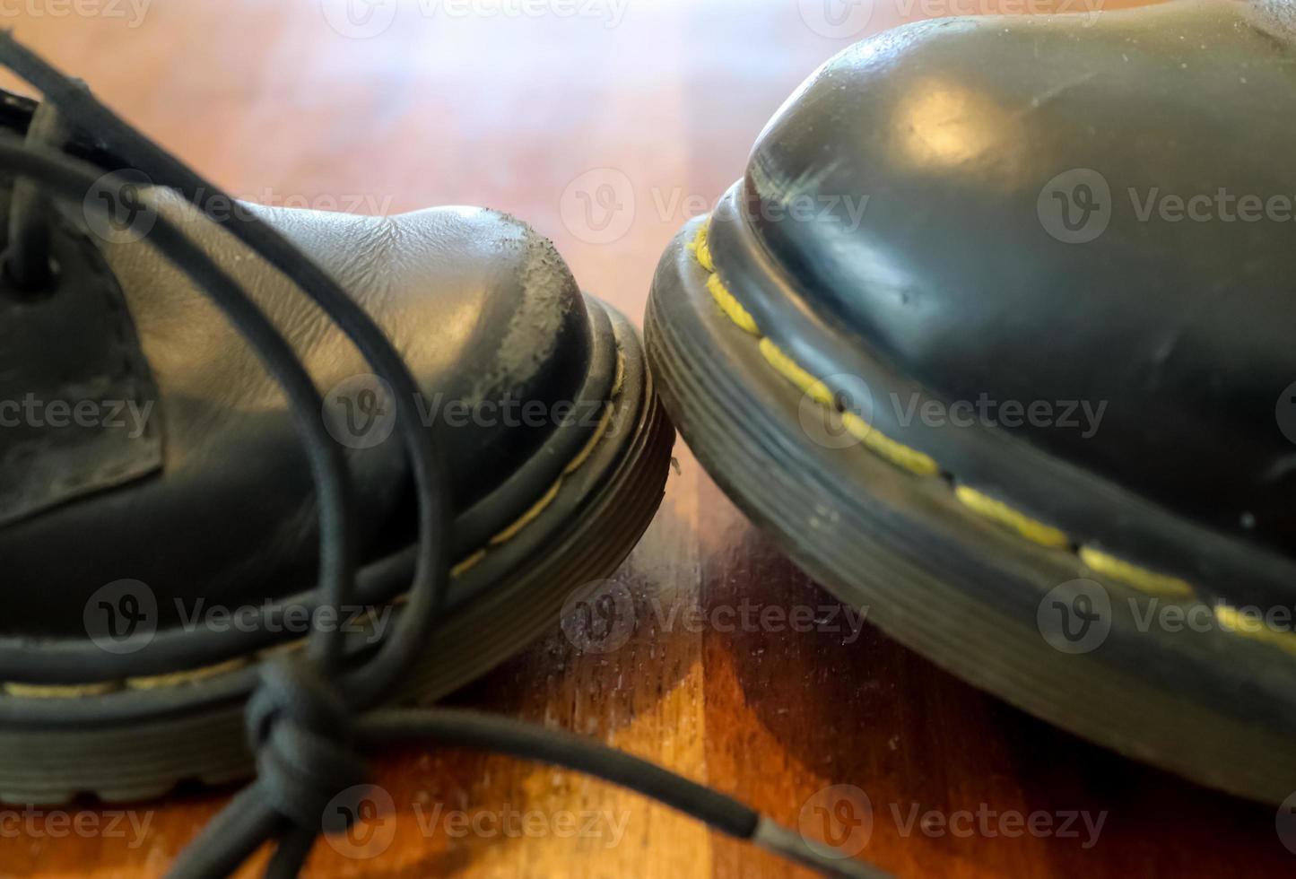 zapato de cuero negro viejo grande y pequeño en un piso de madera foto