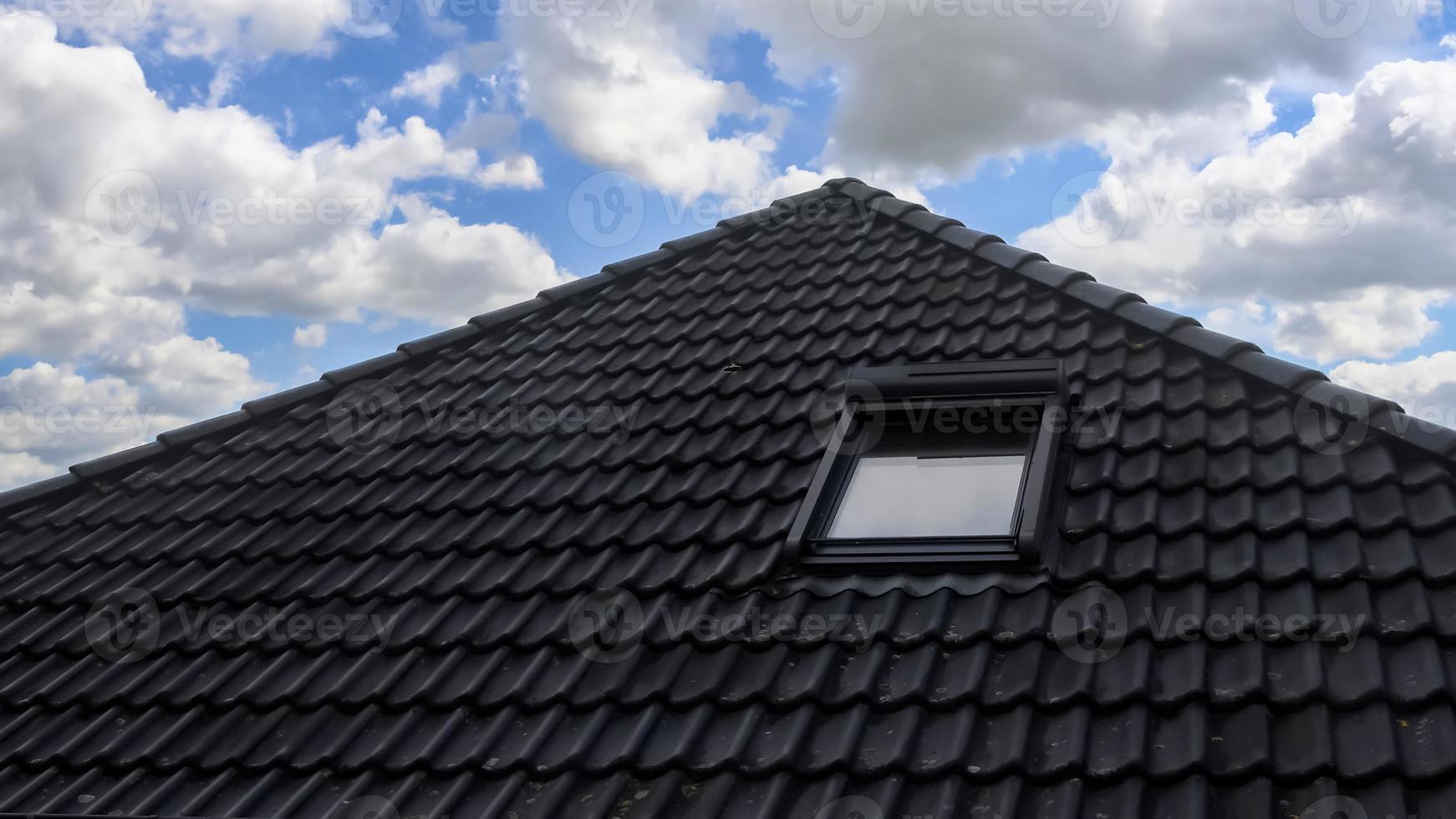 Open roof window in velux style with black roof tiles. photo