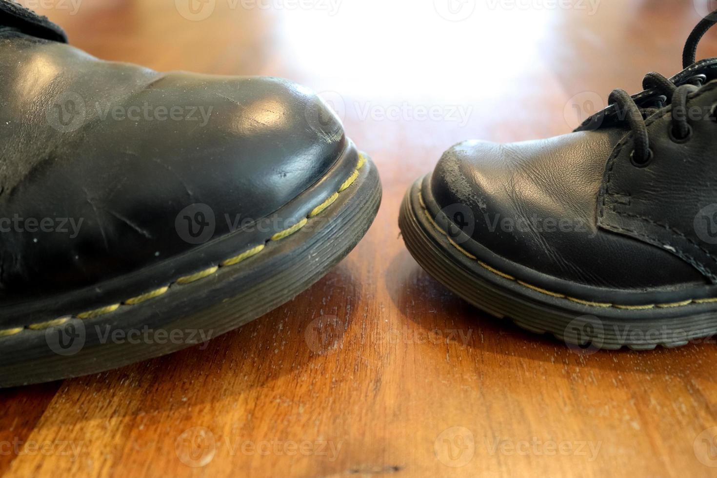 Big and small old black leather shoe on a wooden floor photo