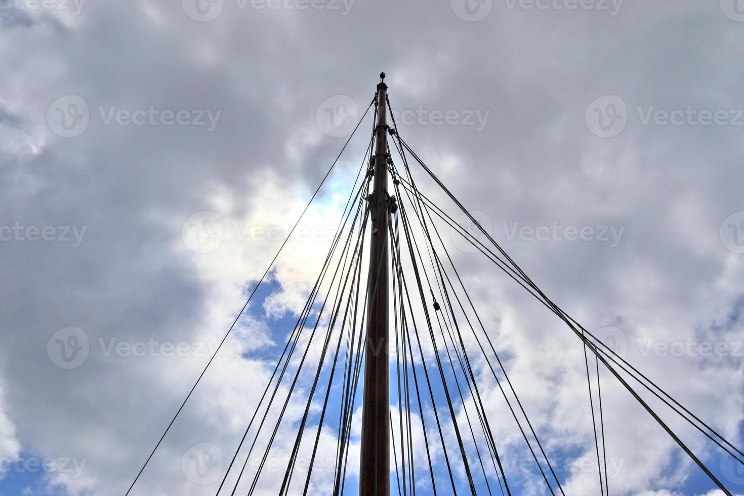 Sailing ship mast against the blue sky on some sailing boats with rigging details. photo