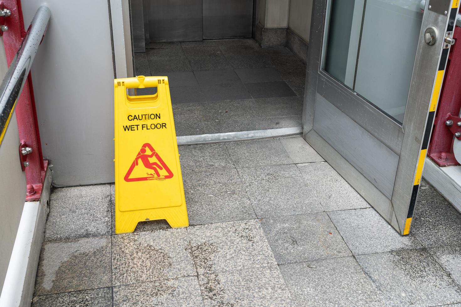 Yellow Caution slippery wet floor sign on the wet ground photo