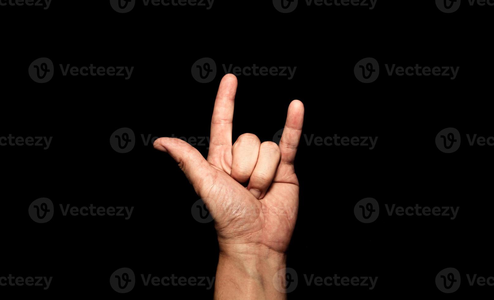 The man's hand holding his finger shows the symbol I love you on a black background. photo