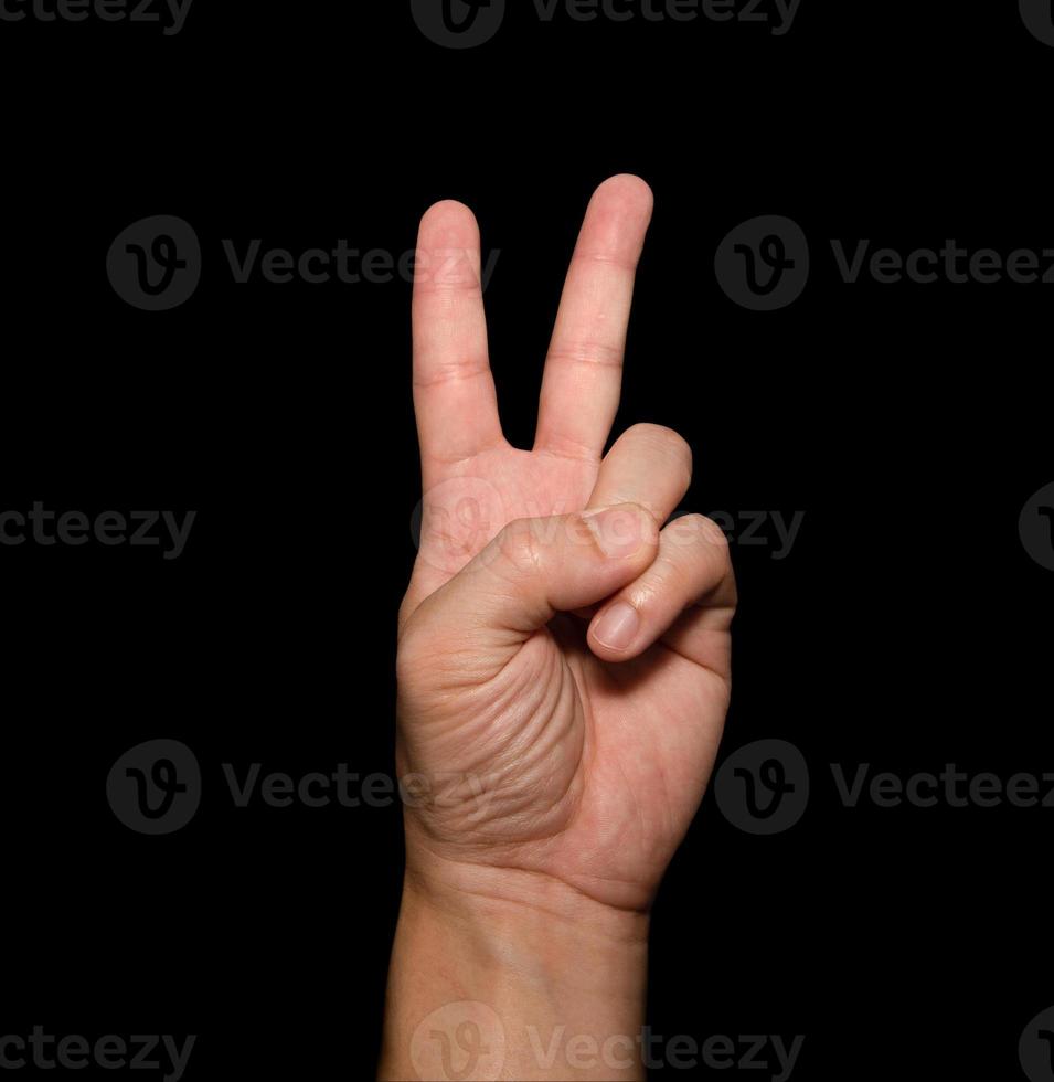 The man's hand that holds two fingers is a V sign, meaning victory. Or still means peace and contempt for challenges on black background photo