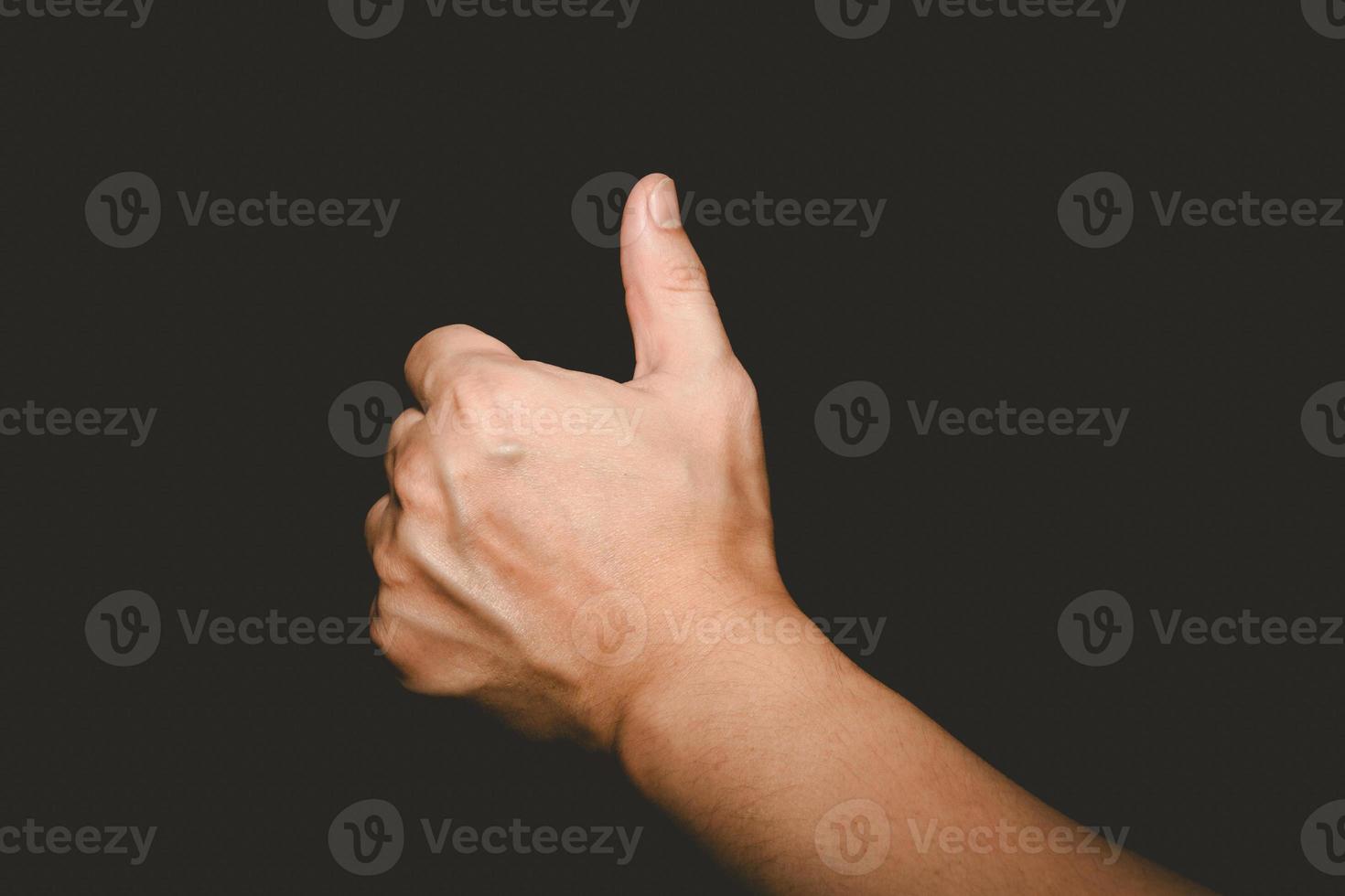 The man's hand that thumbs up is a symbol of admiration on black background photo