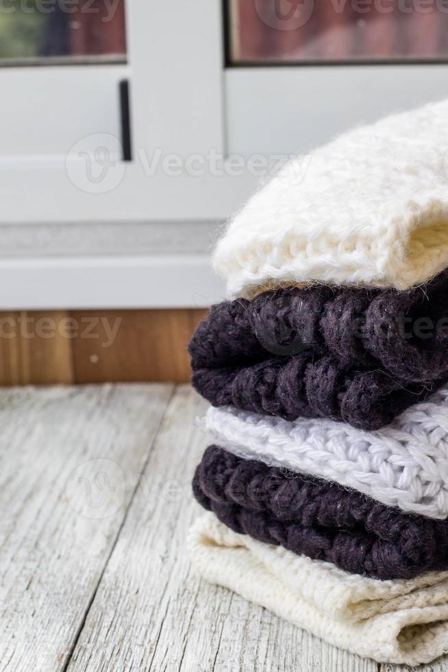 folded knitted things white and black on a white wooden background photo