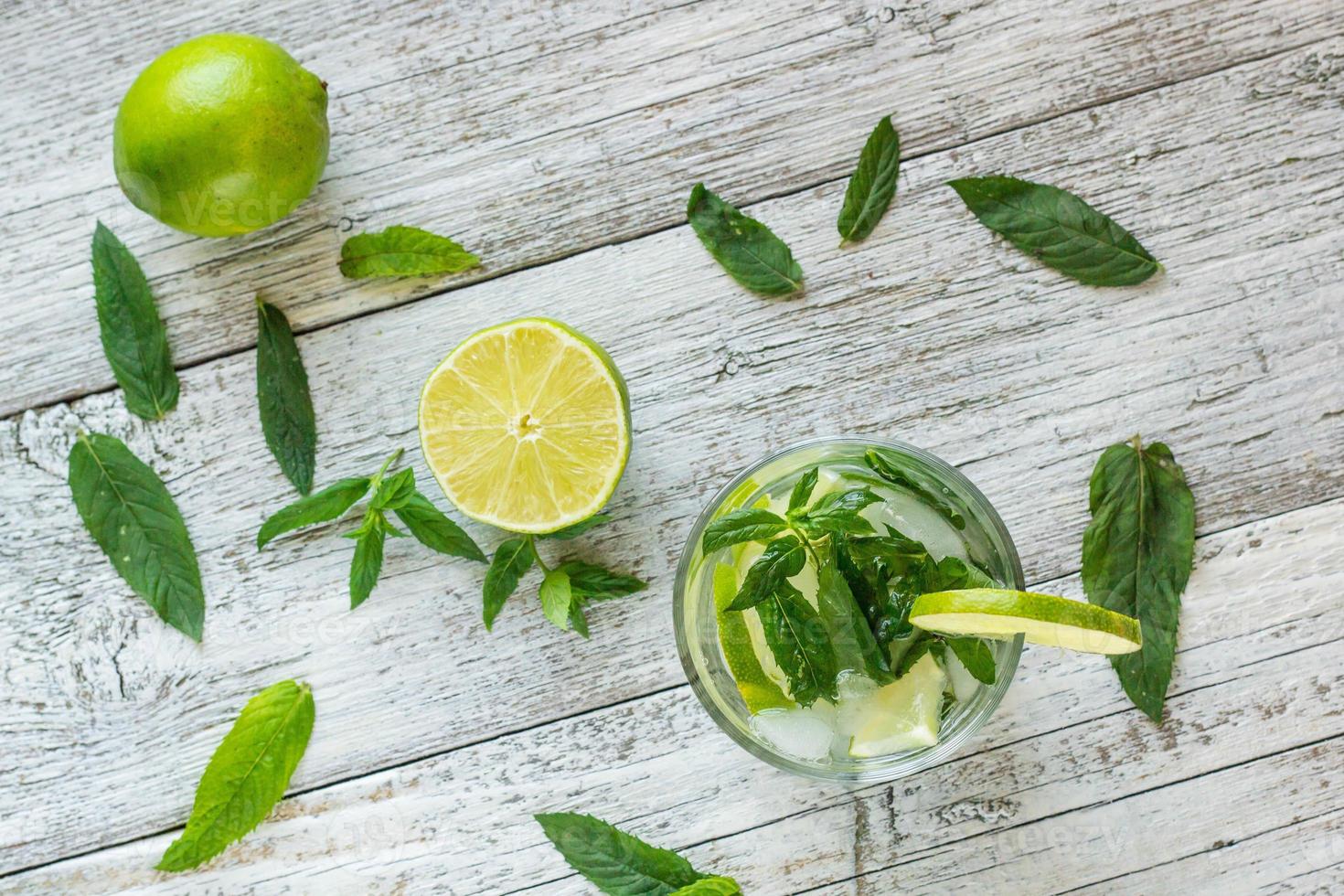 Mojito cocktail with lime and mint in highball glass on a white wooden background Top view photo