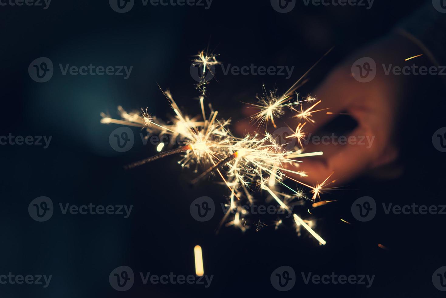 Female hands holding sparkler with night background - bright festive Christmas or New Year Eve photo