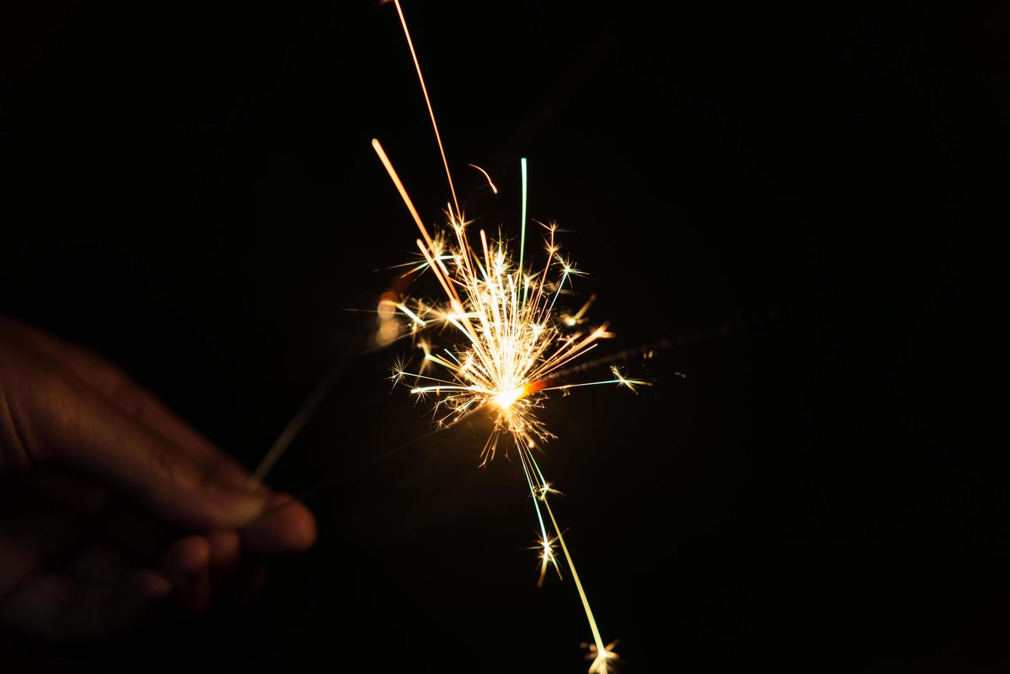Female hands holding sparkler with night background - bright festive Christmas or New Year Eve photo