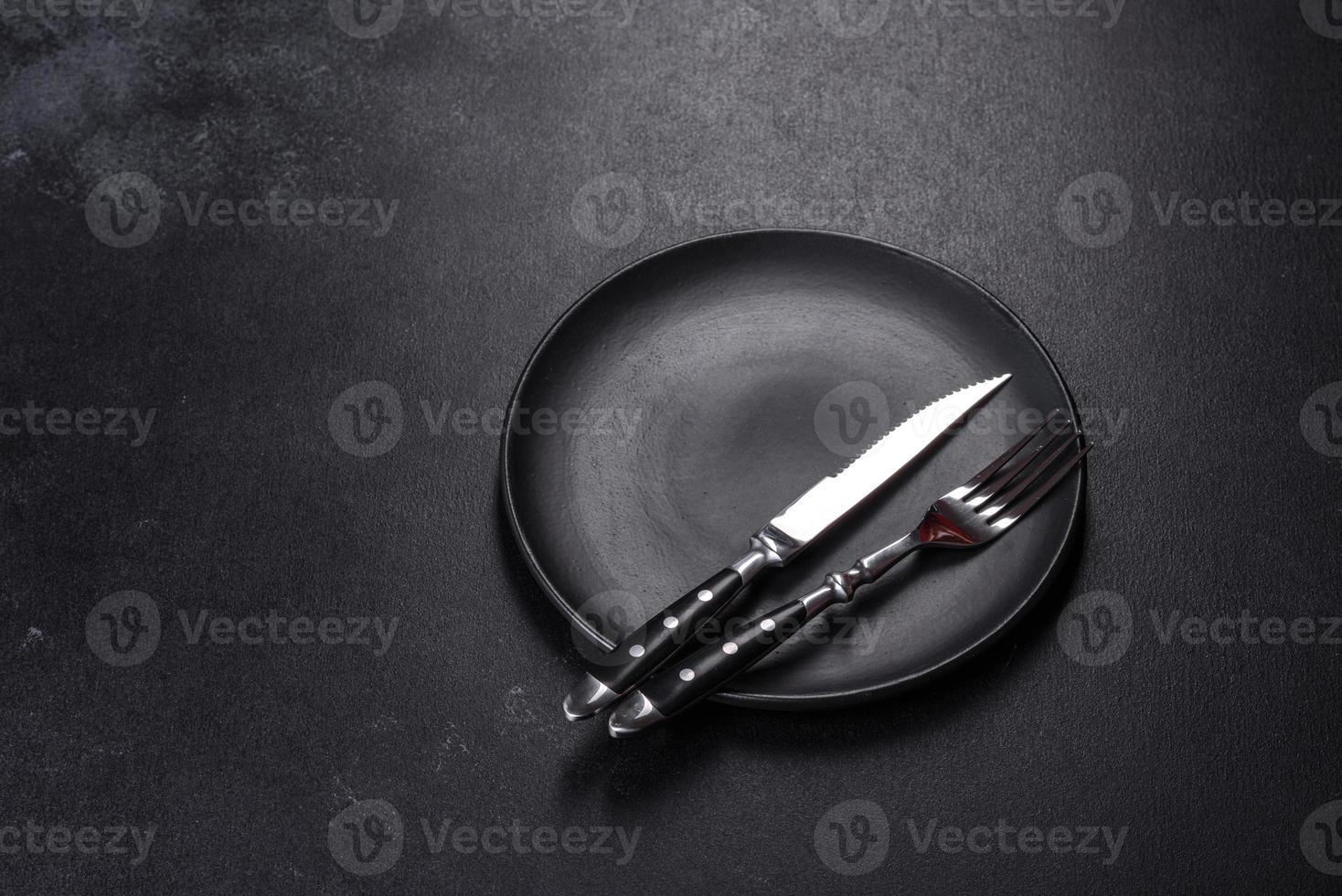 Black plate on a black background. Flat lay, top view, copy space photo