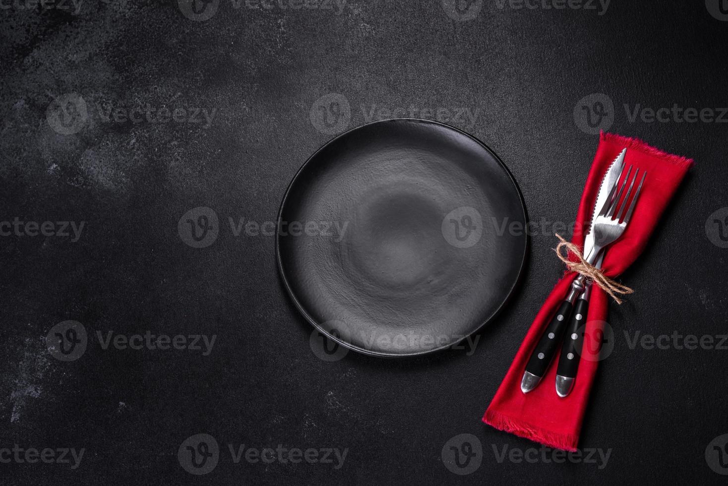 Christmas table setting with empty black ceramic plate, fir tree and black accessories photo