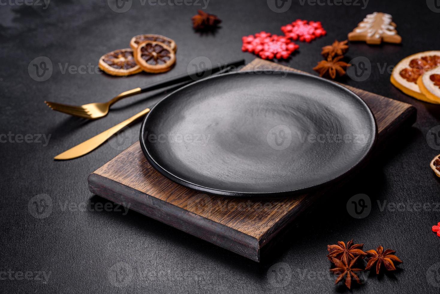 Christmas table setting with empty black ceramic plate, fir tree and black accessories photo