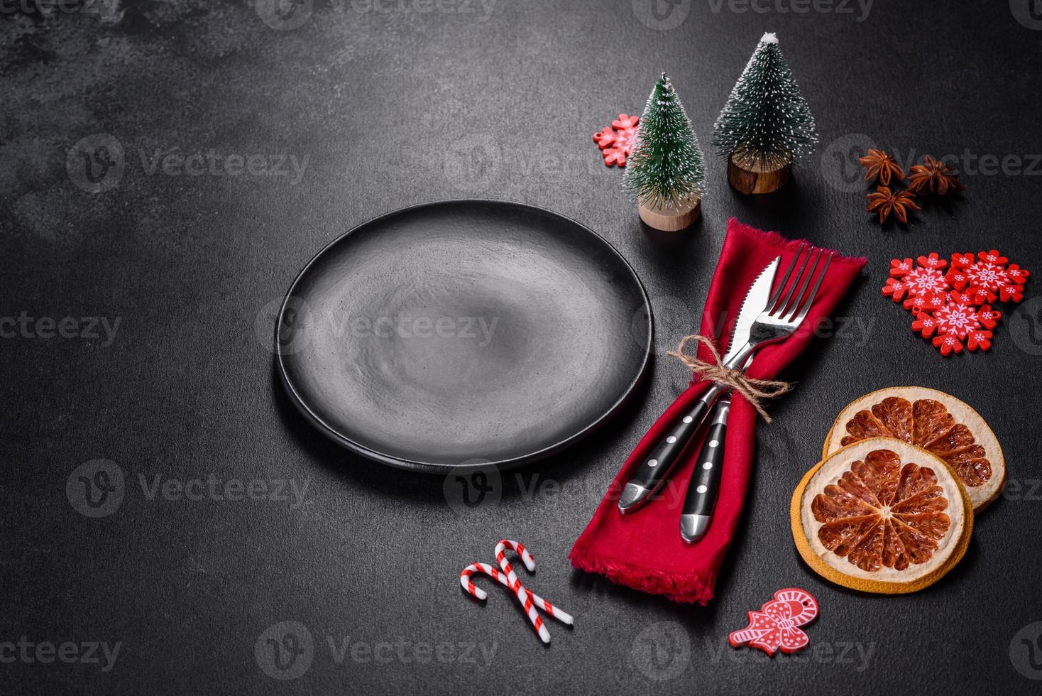Christmas table setting with empty black ceramic plate, fir tree and black accessories photo