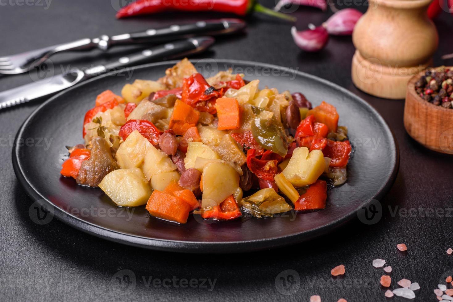 Vegetable stew or ratatouille with eggplant, tomatoes, sweet and hot peppers, onions, carrots and spices in plate photo