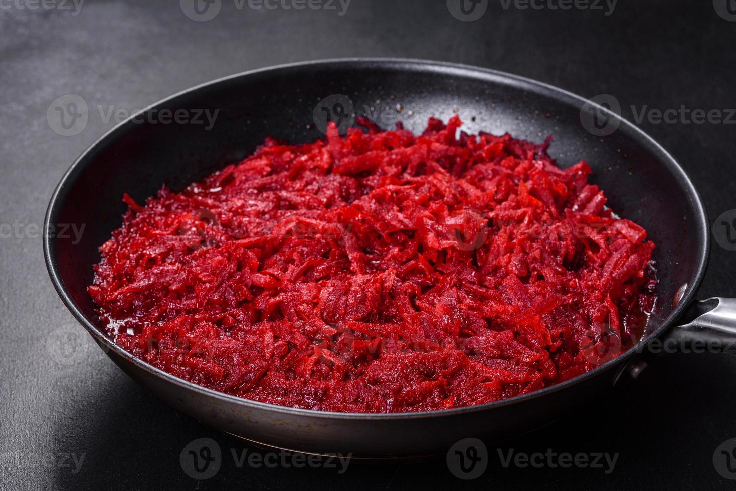 Chopped beetroot in a pan as well as spices and herbs on a wooden cutting board photo