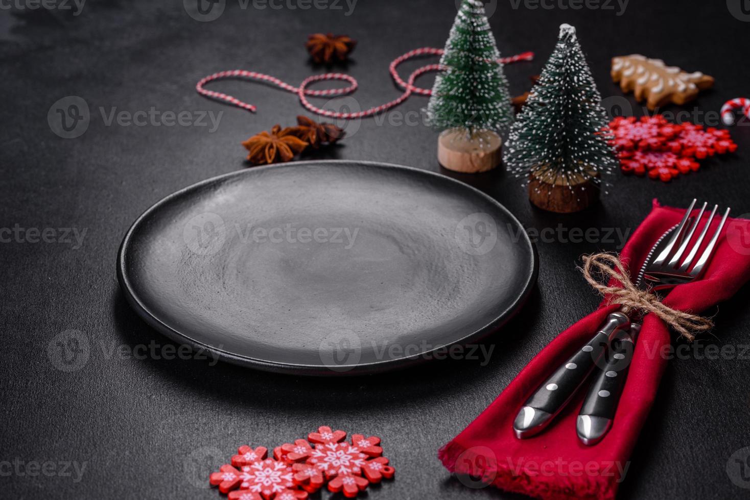 Christmas table setting with empty black ceramic plate, fir tree and black accessories photo