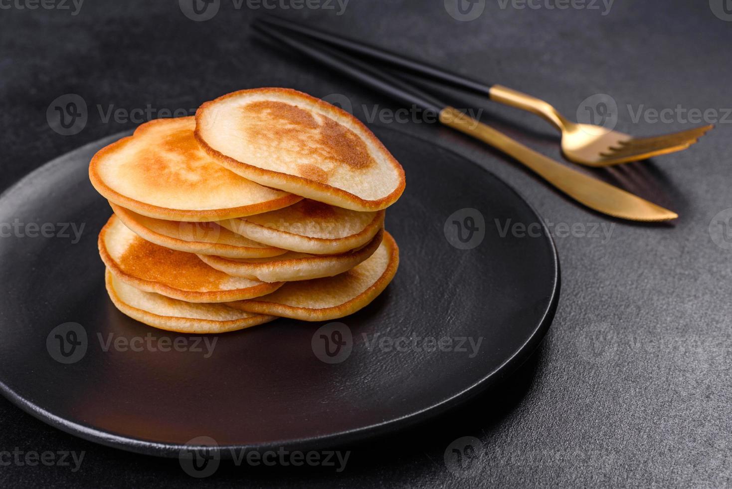 deliciosos panqueques frescos en un plato negro sobre un fondo de hormigón oscuro foto