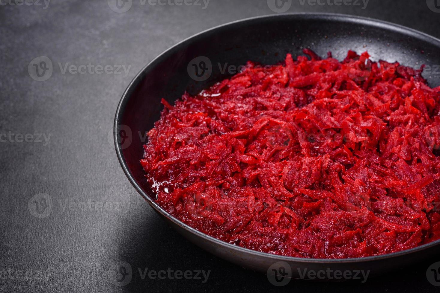 Chopped beetroot in a pan as well as spices and herbs on a wooden cutting board photo