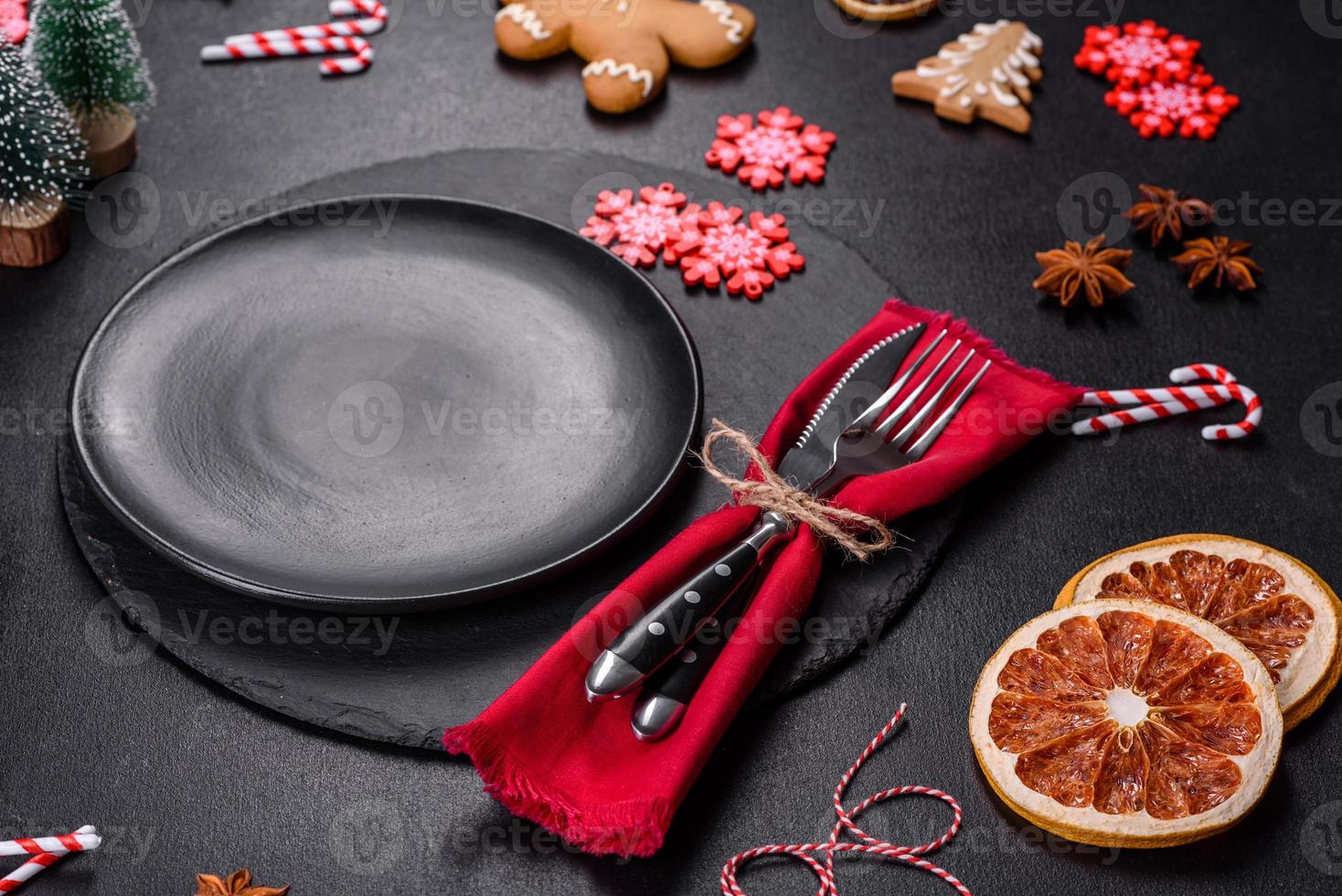 Christmas table setting with empty black ceramic plate, fir tree and black accessories photo