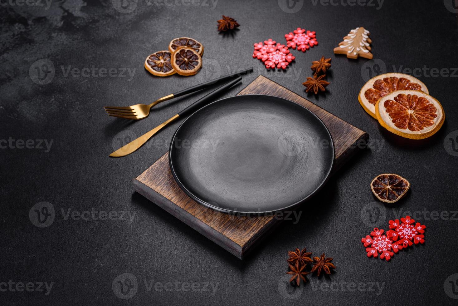 Christmas table setting with empty black ceramic plate, fir tree and black accessories photo