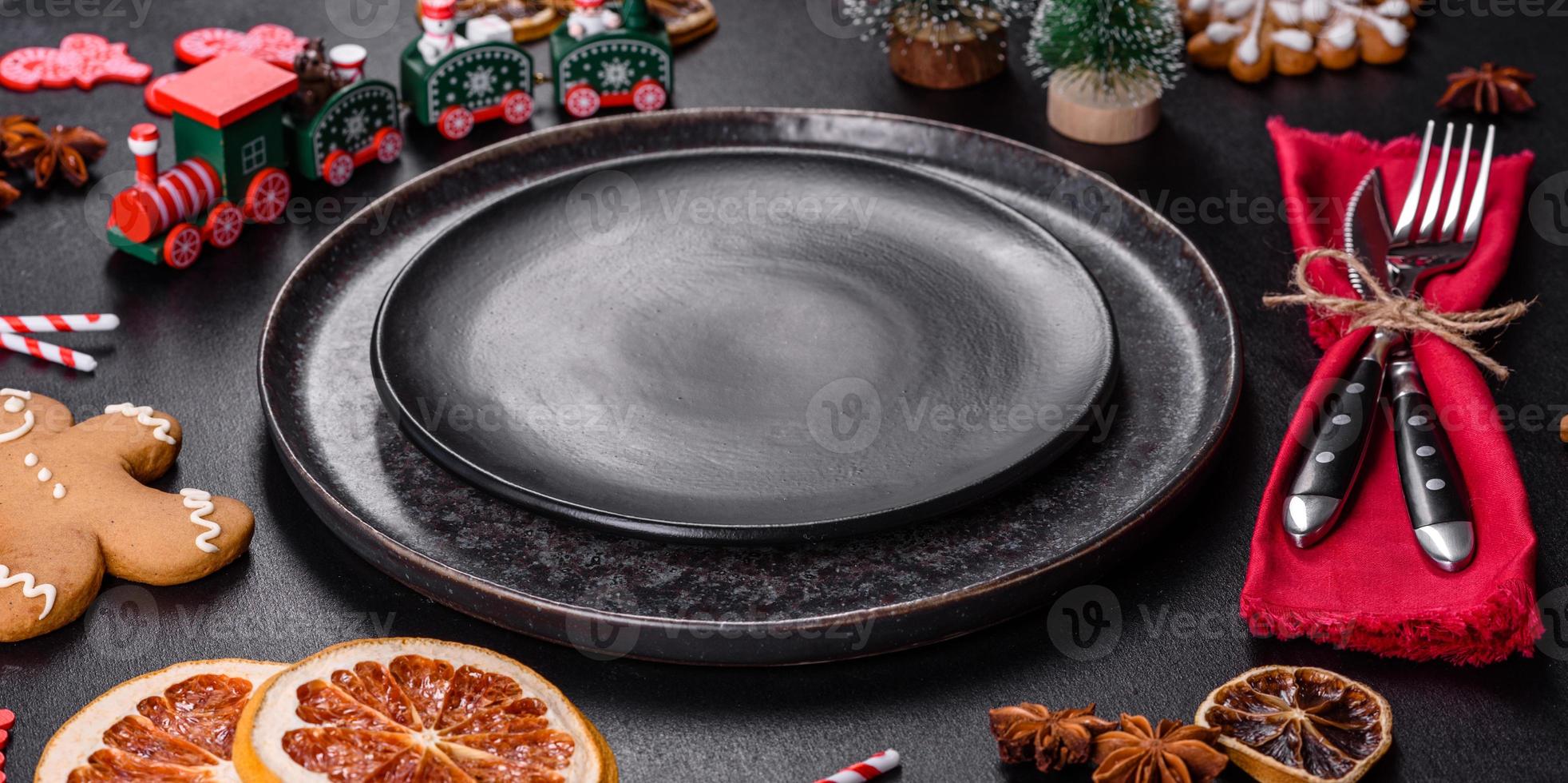 Christmas table setting with empty black ceramic plate, fir tree and black accessories photo