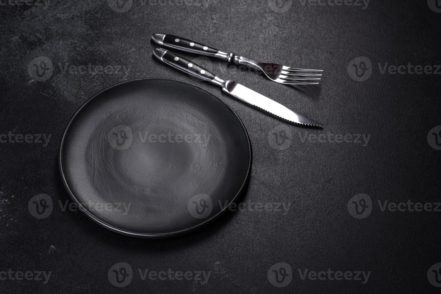 Black plate on a black background. Flat lay, top view, copy space photo