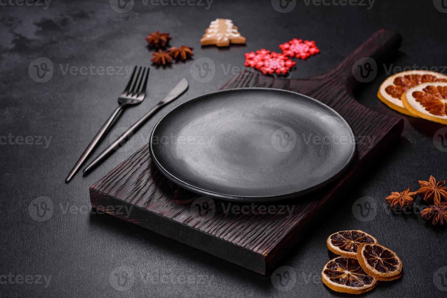 Christmas table setting with empty black ceramic plate, fir tree and black accessories photo