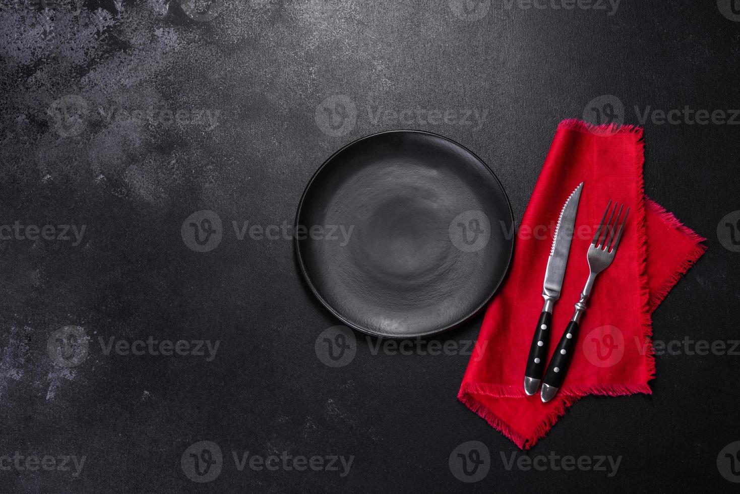 Christmas table setting with empty black ceramic plate, fir tree and black accessories photo