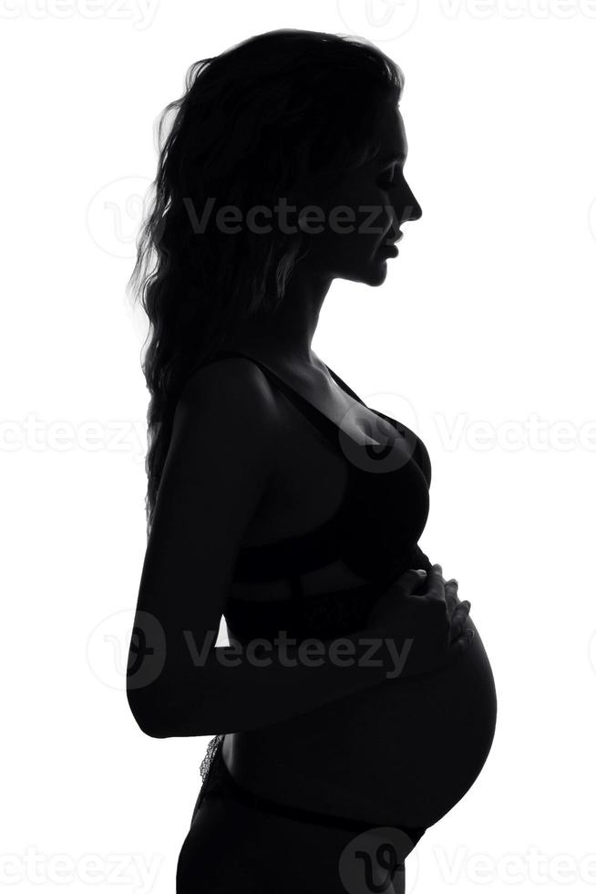 A young white pregnant woman is nine months pregnant on a bright background photo