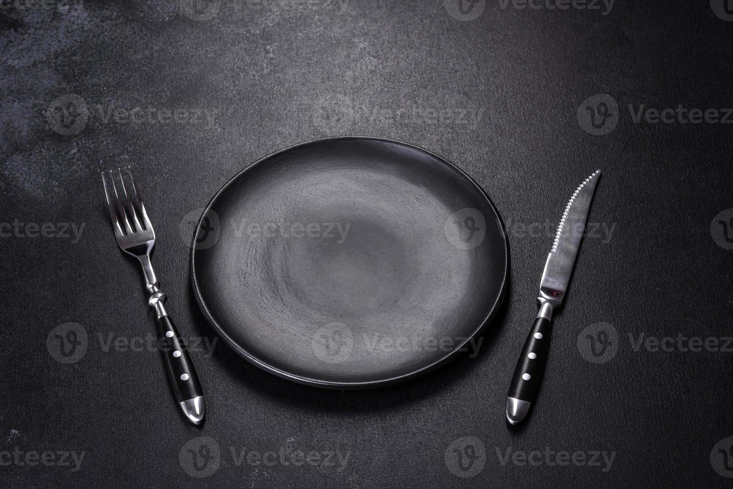 Black plate on a black background. Flat lay, top view, copy space photo