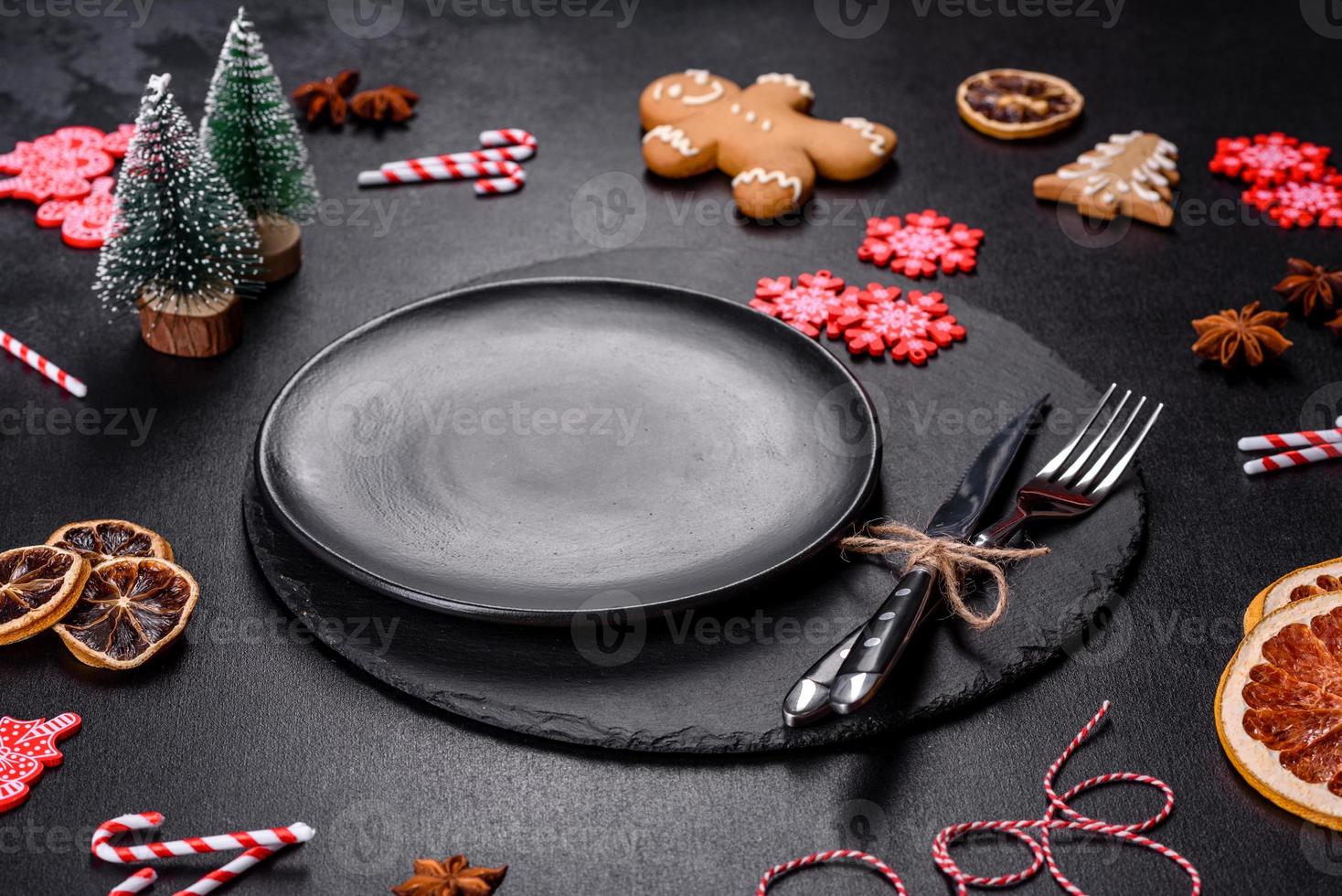 Christmas table setting with empty black ceramic plate, fir tree and black accessories photo