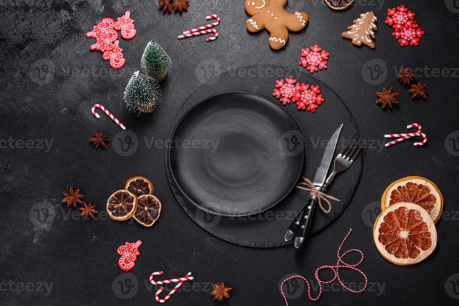 Christmas table setting with empty black ceramic plate, fir tree and black accessories photo