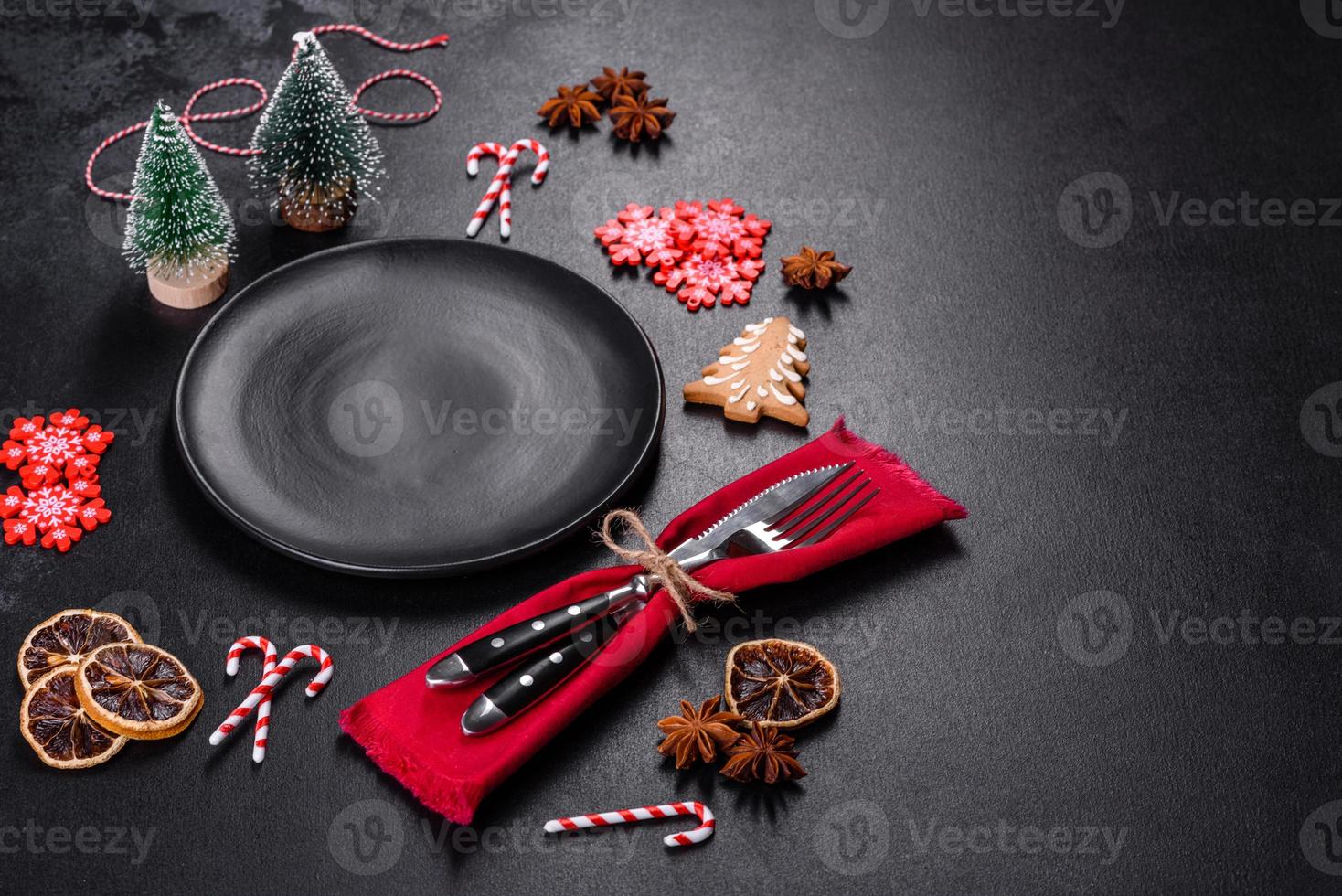 Christmas table setting with empty black ceramic plate, fir tree and black accessories photo
