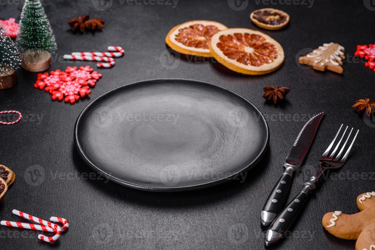 Christmas table setting with empty black ceramic plate, fir tree and black accessories photo