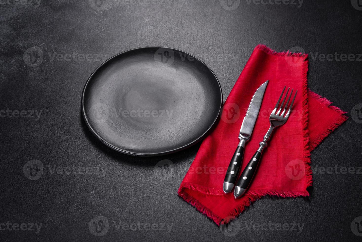 Christmas table setting with empty black ceramic plate, fir tree and black accessories photo