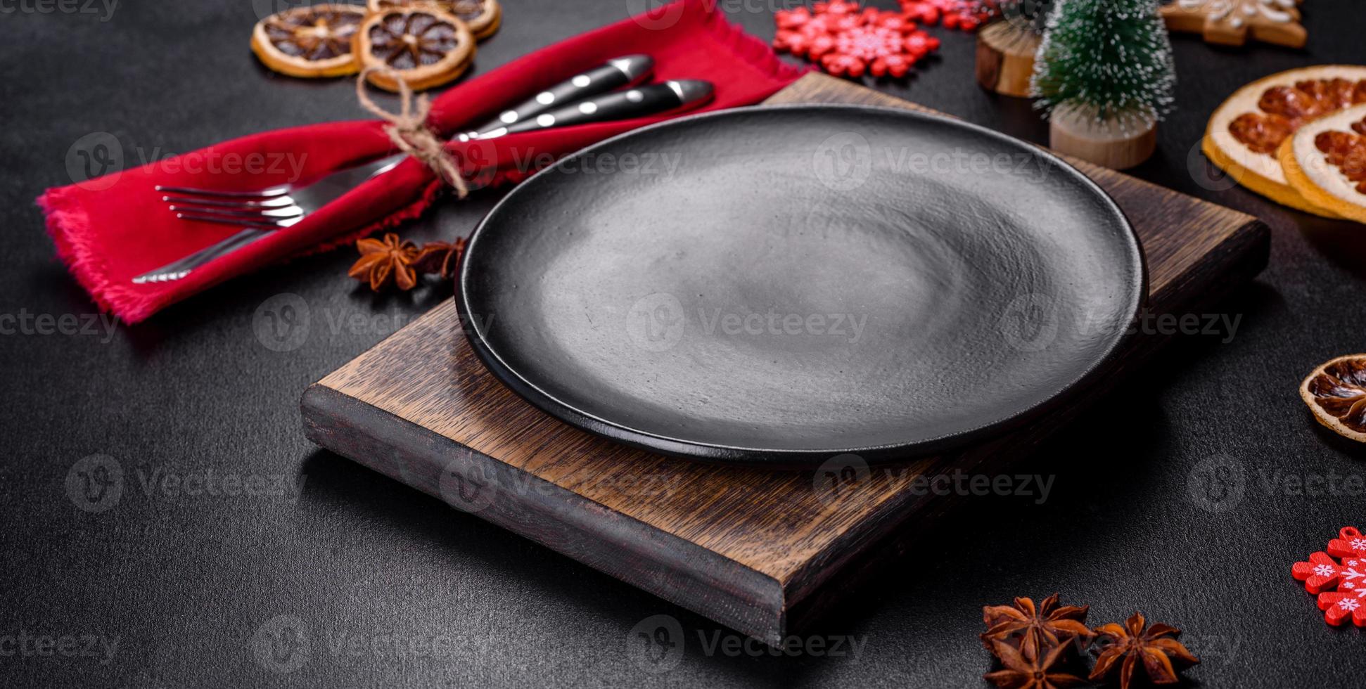 Christmas table setting with empty black ceramic plate, fir tree and black accessories photo