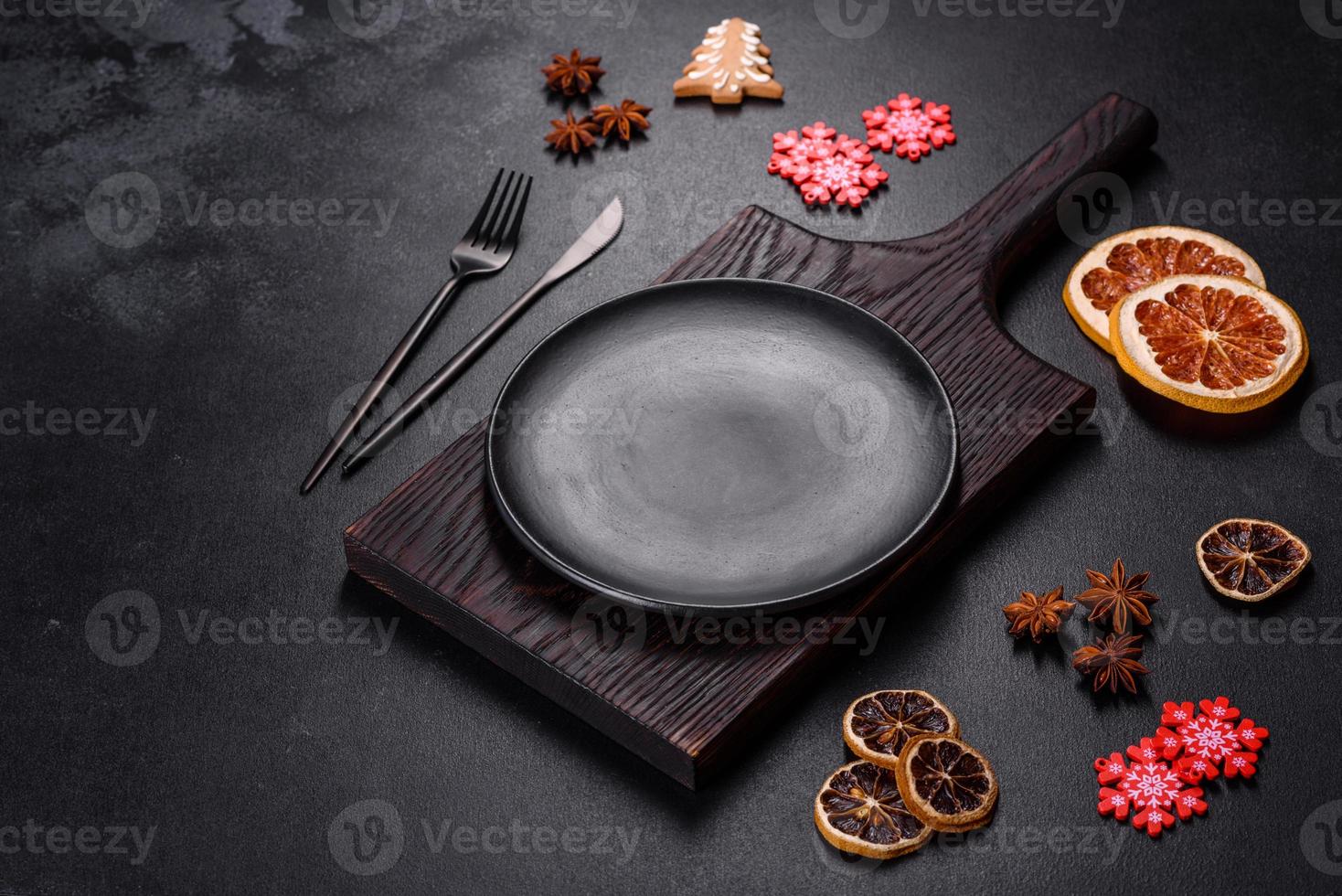 Christmas table setting with empty black ceramic plate, fir tree and black accessories photo
