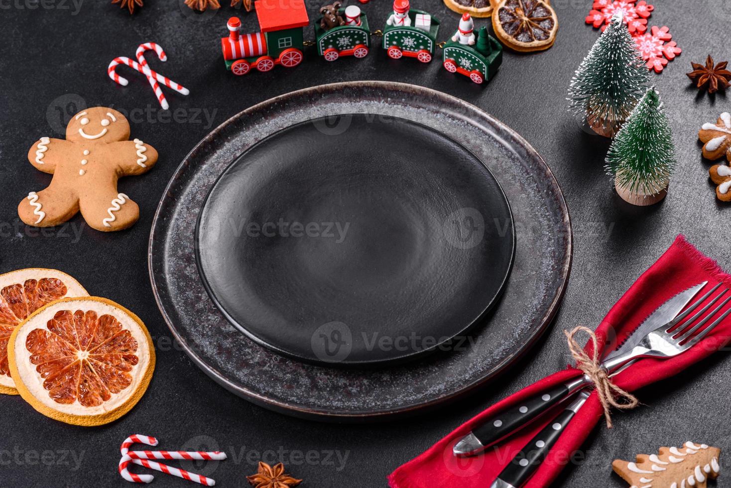Christmas table setting with empty black ceramic plate, fir tree and black accessories photo