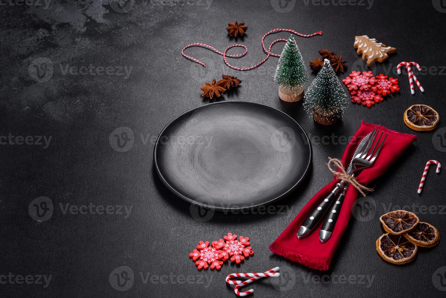 Christmas table setting with empty black ceramic plate, fir tree and black accessories photo