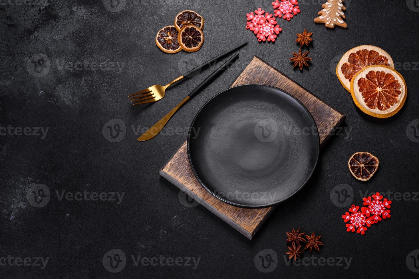 Christmas table setting with empty black ceramic plate, fir tree and black accessories photo