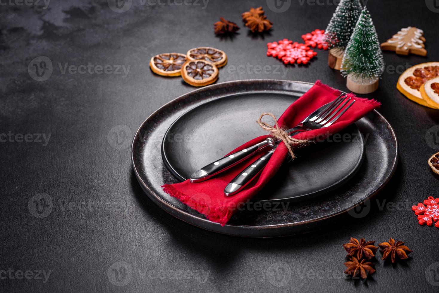 Christmas table setting with empty black ceramic plate, fir tree and black accessories photo
