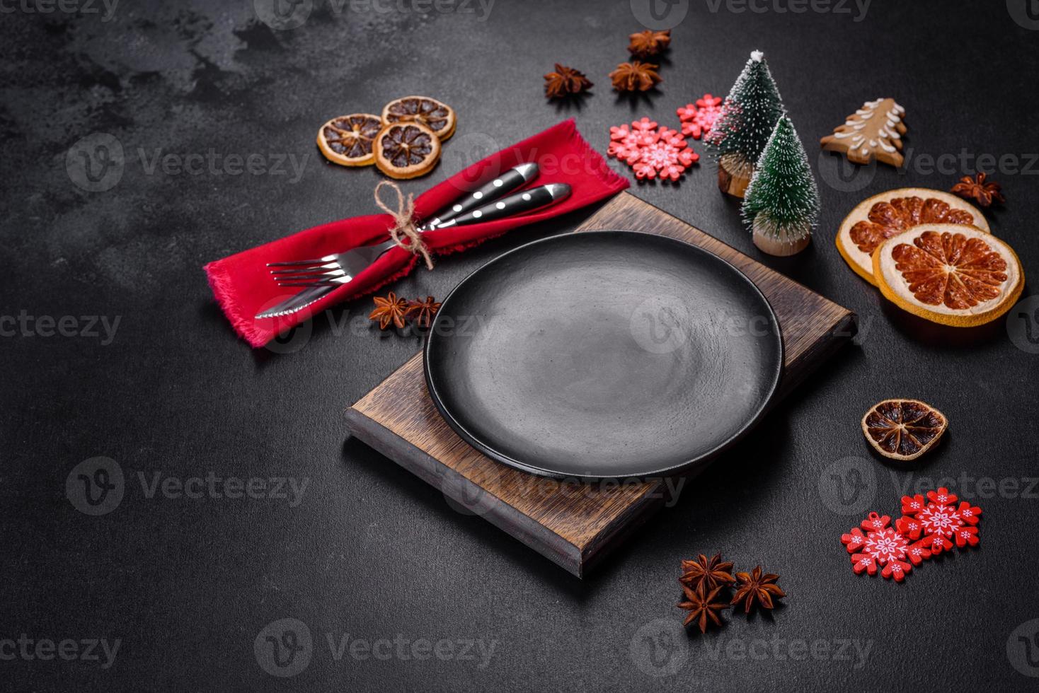 Christmas table setting with empty black ceramic plate, fir tree and black accessories photo