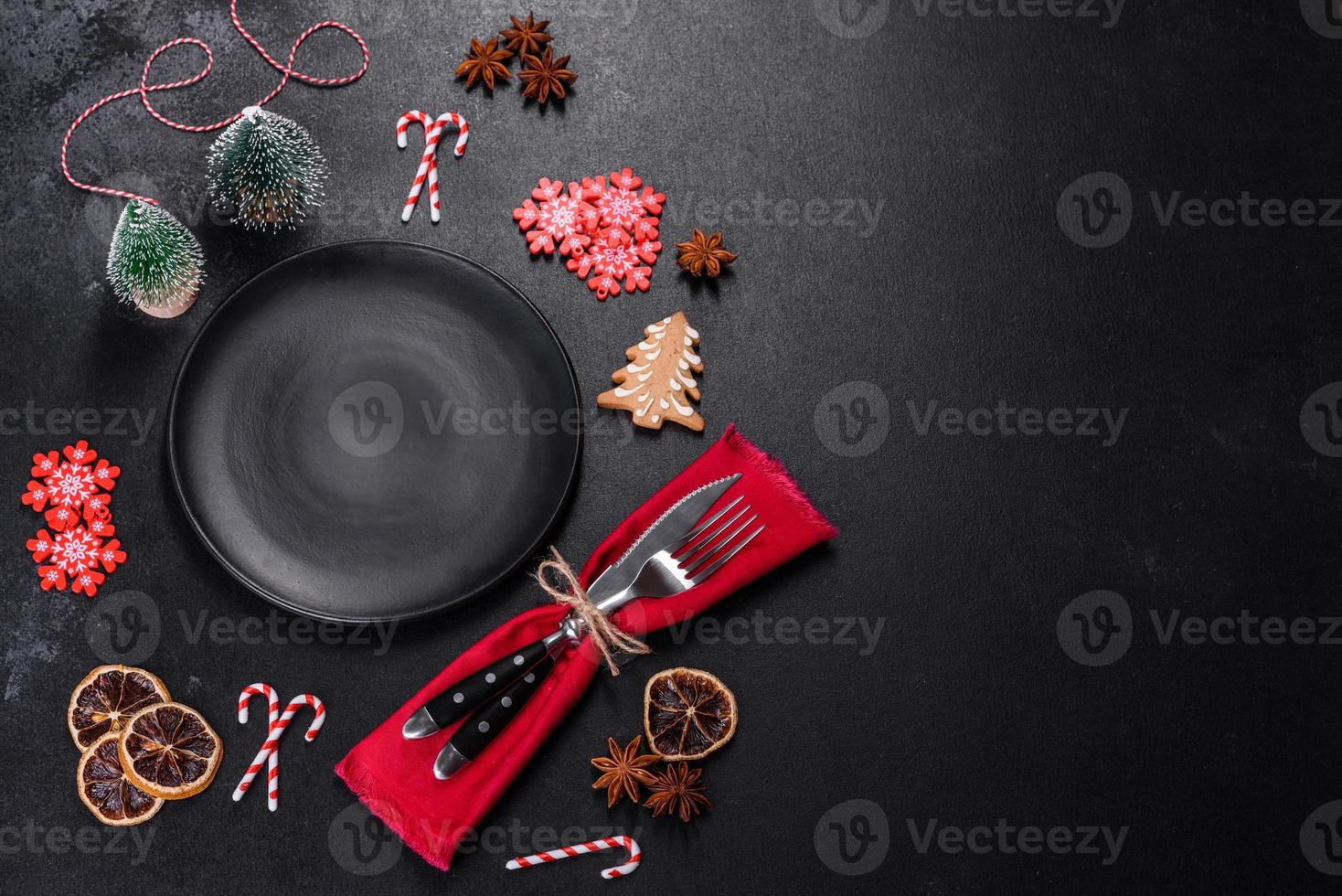 Christmas table setting with empty black ceramic plate, fir tree and black accessories photo