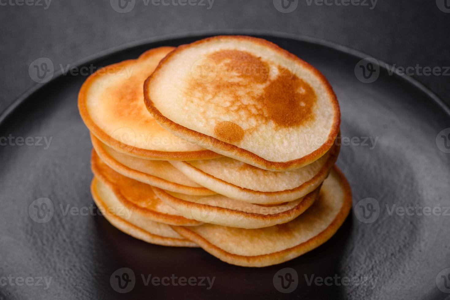 deliciosos panqueques frescos en un plato negro sobre un fondo de hormigón oscuro foto