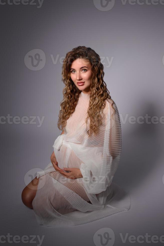 A young white pregnant woman is nine months pregnant on a bright background photo