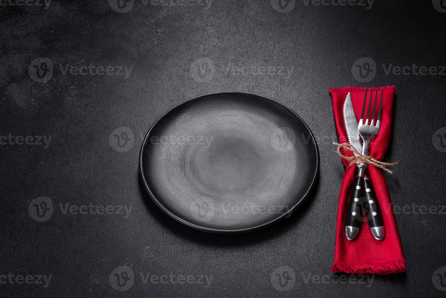 Christmas table setting with empty black ceramic plate, fir tree and black accessories photo